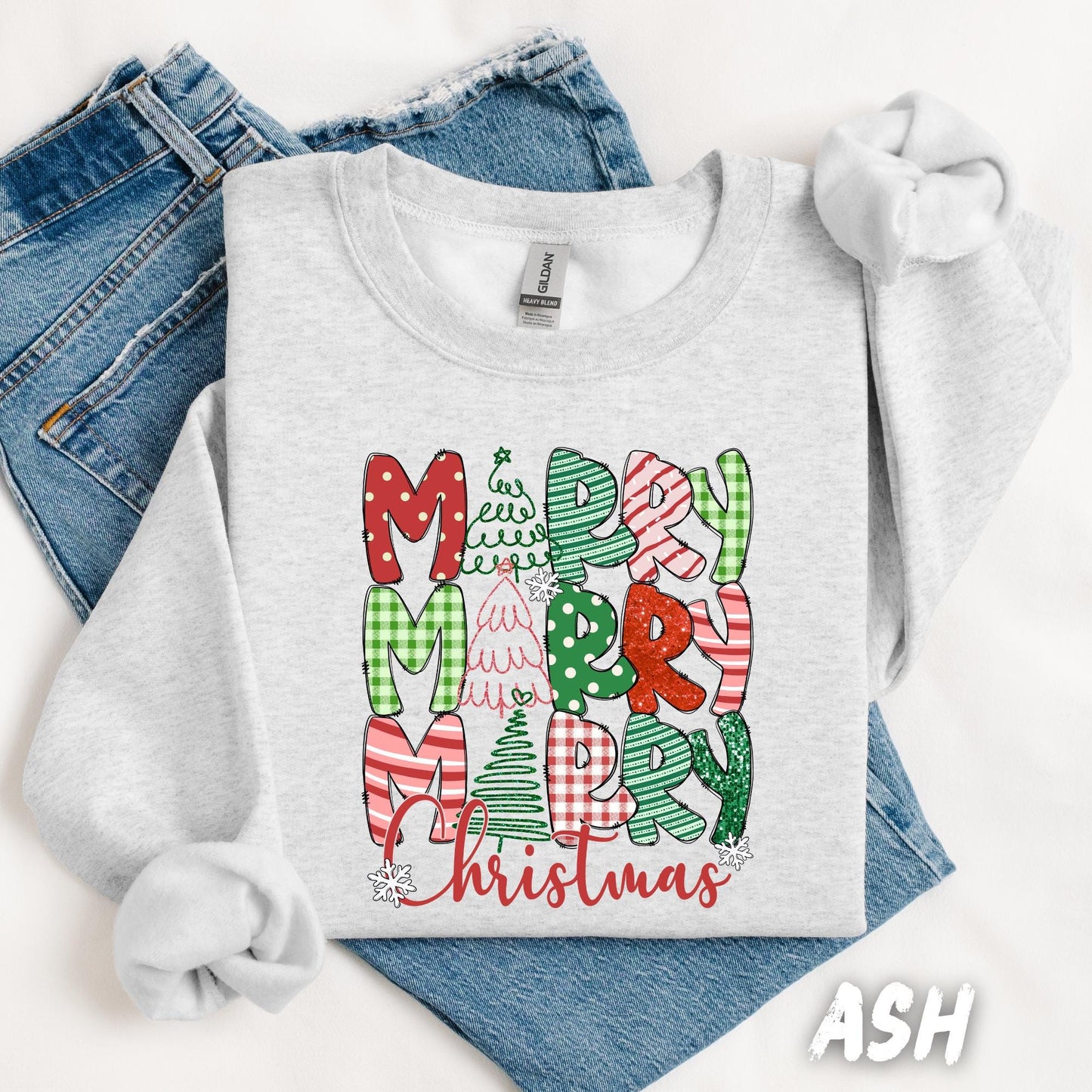 A cozy white sweatshirt featuring the phrase "Merry Merry Merry Christmas" in festive fonts and patterns with Christmas trees and snowflakes.