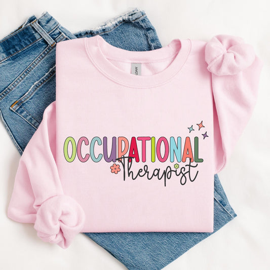 sweatshirt with &quot;Occupational Therapist&quot; in playful, multicolored letters, accented with small flowers and stars, creating a cheerful and vibrant design.