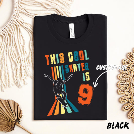 t-shirt featuring a colorful retro design with the text &quot;This Cool Skater is 9&quot; in bold, distressed letters. A silhouette of a skateboarder performing a trick appears in front of vertical rainbow stripes. The number &quot;9&quot; is large and orange, with an arrow pointing to it labeled &quot;Custom Age,&quot; indicating the number can be personalized. The shirt is styled flat on a cream background with decorative macramé and palm leaf elements.