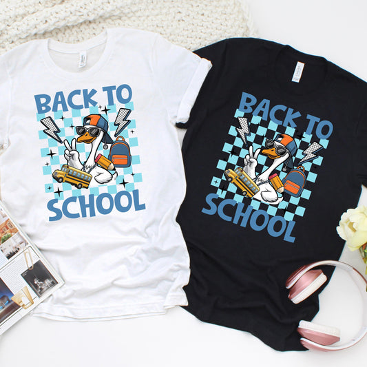 Trendy back to school t-shirts featuring a cartoon duck in sunglasses, snapback hat, and chain, flashing a peace sign and holding a pencil, backpack, and school bus – bold &#39;Back to School&#39; text with a blue checkerboard background – fun design available on white and black shirts, ideal for students.