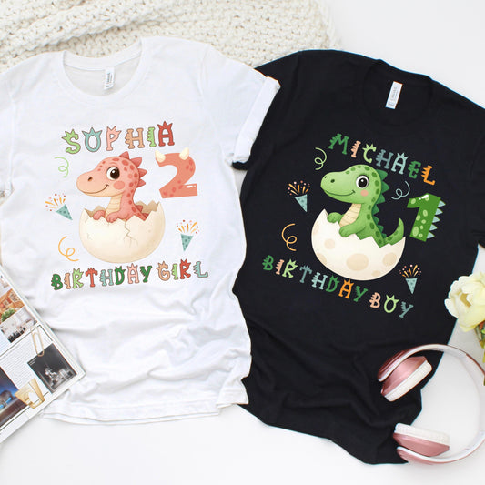 custom kids’ birthday shirts featuring adorable baby dinosaurs hatching from eggs, personalized with the child’s name and age. One shirt has a pink dinosaur for &quot;custom kid name&quot; with the text “Birthday Girl,” while the other has a green dinosaur for &quot;custom kid name&quot; with the text “Birthday Boy,” decorated with confetti and party elements.