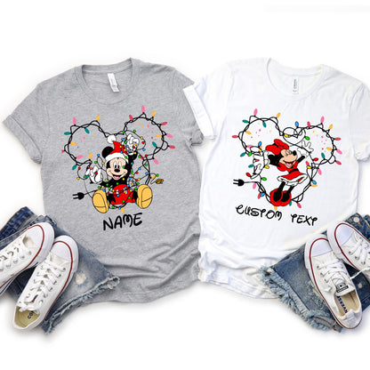 Customizable Christmas shirt featuring Disney Mickey and Friends character tangled in holiday lights forming mouse ears shape. Personalize with any name or text, choose from 6 character designs.