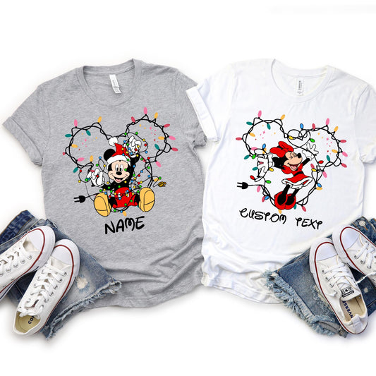 Customizable Christmas shirt featuring Disney Mickey and Friends character tangled in holiday lights forming mouse ears shape. Personalize with any name or text, choose from 6 character designs.