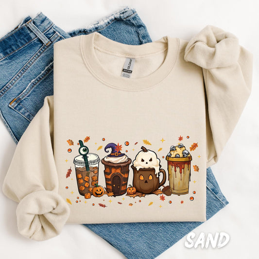 sweatshirt with a fun Halloween-themed design of five festive drinks, each decorated with spooky details like a witch hat, ghost face, eyeball stirrer, skulls, pumpkins, and dripping syrup, surrounded by autumn leaves and stars