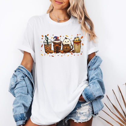 Shirt with a fun Halloween-themed design of five festive drinks, each decorated with spooky details like a witch hat, ghost face, eyeball stirrer, skulls, pumpkins, and dripping syrup, surrounded by autumn leaves and stars.