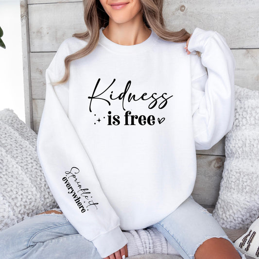 Unisex white sweatshirt with motivational quote “Kindness is free” on the front and “Sprinkle it everywhere” on the sleeve. Cozy positive message pullover for women and men, perfect casual outfit, self-love gift, or kindness graphic sweatshirt for everyday wear.