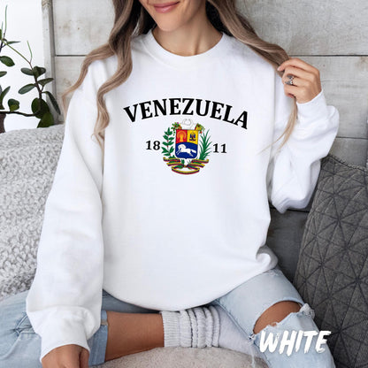 Unisex white sweatshirt with “Venezuela” text, the Venezuelan national coat of arms, and the year 1811 printed on the front. Cozy crewneck sweater celebrating Venezuelan heritage, culture, and independence. Perfect gift for Venezuelans, expats, and anyone proud of their roots.