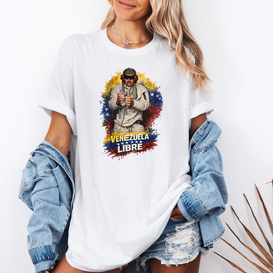 Illustration Maduro wearing protective goggles and earmuffs, holding a plastic water bottle, standing in front of a painted splash background in the colors of the Venezuelan flag. Bold text at the bottom reads ‘Venezuela Libre’ with stars underneath, symbolizing freedom and national pride.