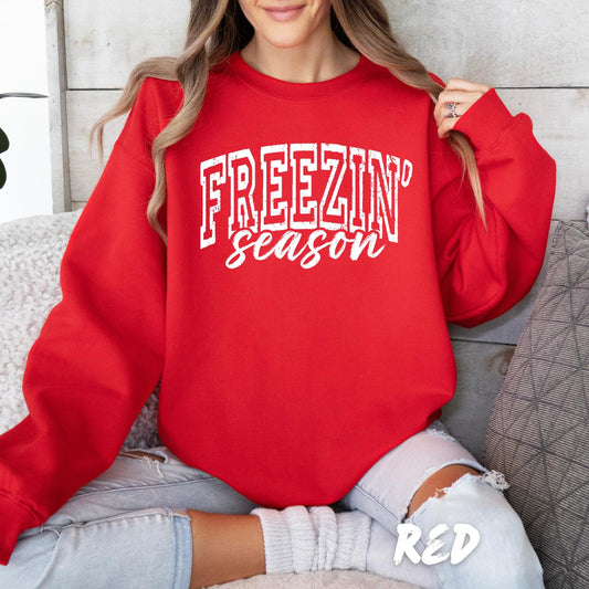 Woman wearing a red crewneck sweatshirt with white ‘Freezin Season’ text, cozy winter casual outfit.