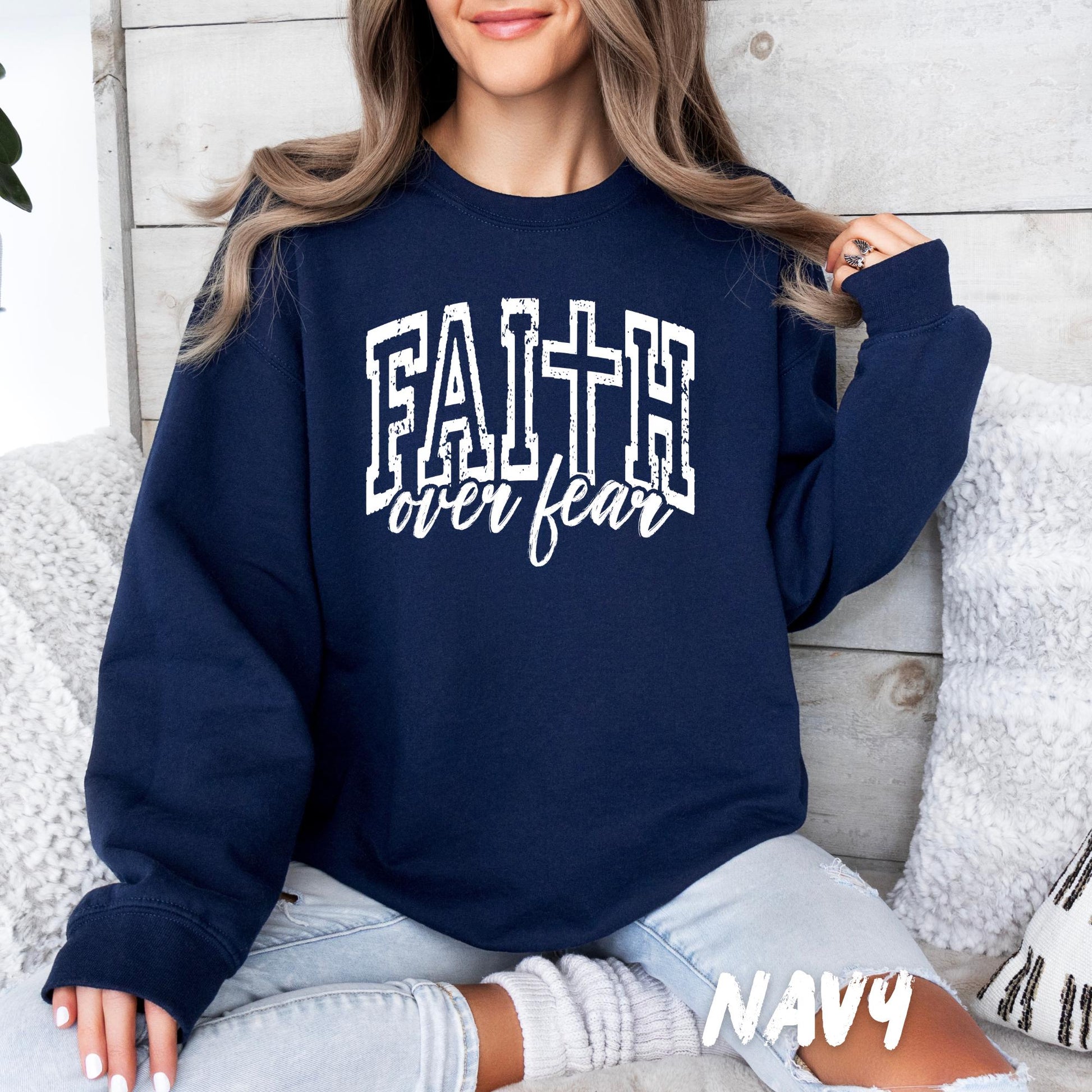 Woman wearing a navy blue crewneck sweatshirt with white ‘Faith over Fear’ text, cozy casual outfit.