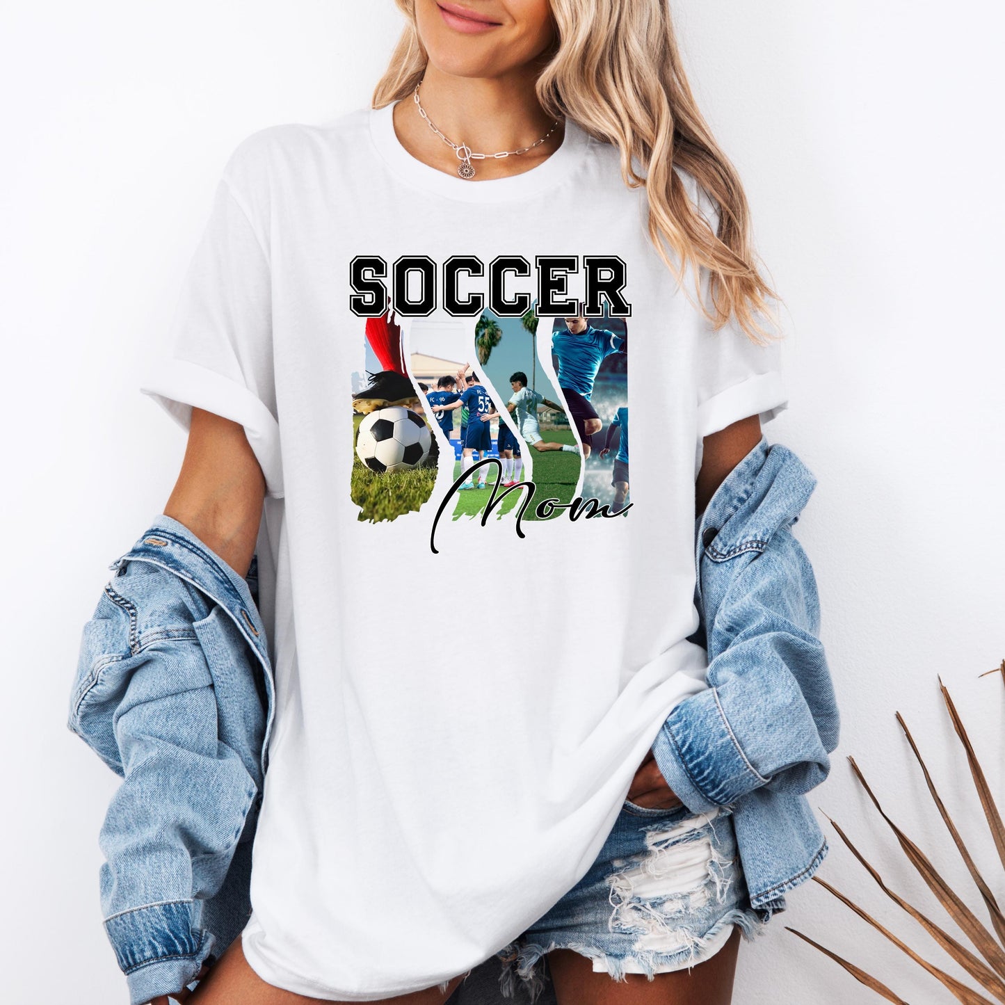 t-shirt featuring a "Soccer Mom" graphic design with collage images of soccer players, soccer ball, and action shots. The model is wearing a casual white tee with denim shorts and a jean jacket, showing a stylish sports mom shirt perfect for soccer games, team support, and proud soccer moms.