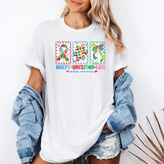 Autism awareness shirt with colorful puzzle ribbon, puzzle piece, and bow design, featuring the phrase “Accept Understand Love” on a white t-shirt, worn casually with denim jacket and shorts.