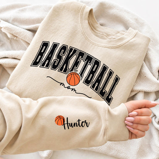 Basketball mom sweatshirt with bold varsity lettering and basketball graphic, personalized sleeve name design, cozy sports mom crewneck