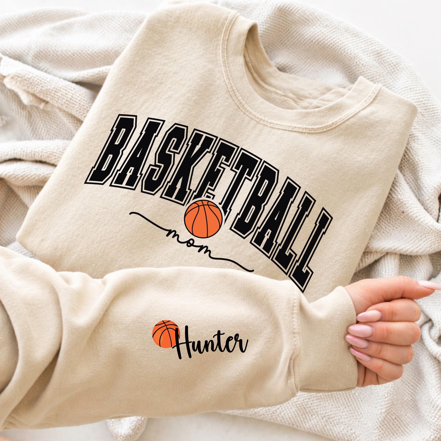 Basketball mom sweatshirt with bold varsity lettering and basketball graphic, personalized sleeve name design, cozy sports mom crewneck