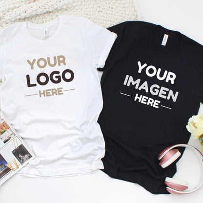 A Unisex t-shirt with the text YOUR LOGO HERE in tan and dark brown, and a black t-shirt with the text YOUR IMAGEN HERE in white. Both shirts feature short sleeves and a crew neckline, presented as a pair of customizable garments.