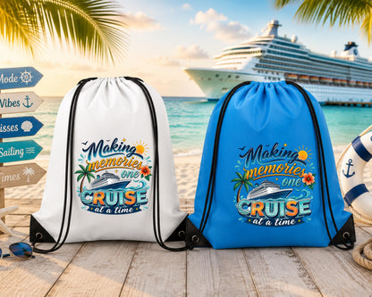 White and sky blue drawstring backpacks featuring a colorful "Making Memories One Cruise at a Time" design displayed on a tropical beach with a cruise ship in the background.