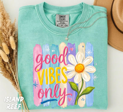 Retro Good Vibes Only graphic featuring colorful pastel paint brushstrokes, a large white daisy flower, and groovy hand-lettered typography printed on an Island Reef Comfort Colors t-shirt.