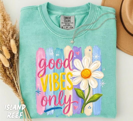 Retro Good Vibes Only graphic featuring colorful pastel paint brushstrokes, a large white daisy flower, and groovy hand-lettered typography printed on an Island Reef Comfort Colors t-shirt.