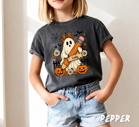 Comfort Colors 9018 youth white t-shirt featuring a personalized ghost holding a pencil with custom child name, pumpkins, flowers, bats, and cute Halloween back to school design.