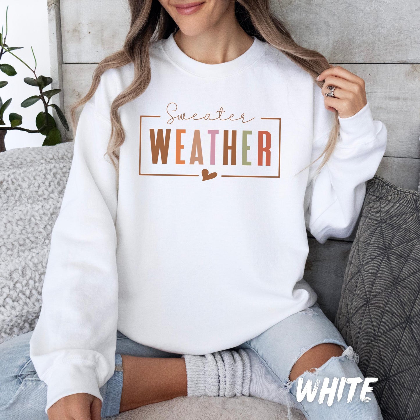 White unisex sweatshirt with “Sweater WEATHER” design in multicolor fall tones and a small heart detail. Cozy autumn pullover for adults and kids, perfect for fall weather, Thanksgiving, and casual seasonal outfits. Available in a variety of colors.