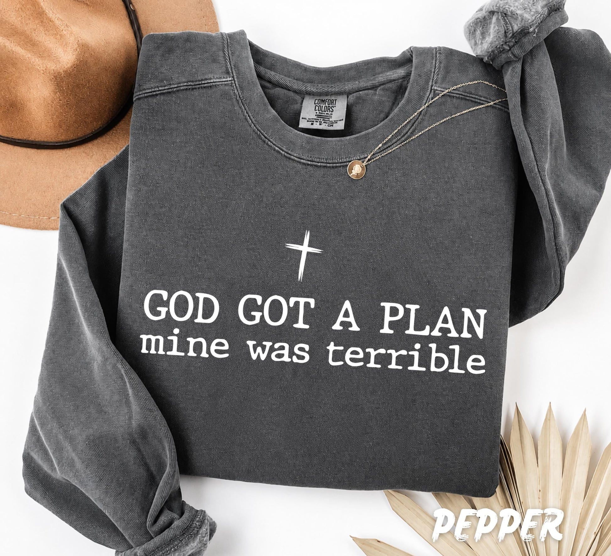 Comfort Colors unisex swetshirt featuring the inspirational quote "God Got A Plan, Mine Was Terrible" with a minimalist cross design in black typography on a white garment-dyed shirt.