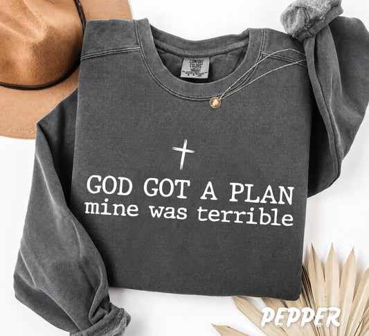 Comfort Colors unisex swetshirt featuring the inspirational quote "God Got A Plan, Mine Was Terrible" with a minimalist cross design in black typography on a white garment-dyed shirt.