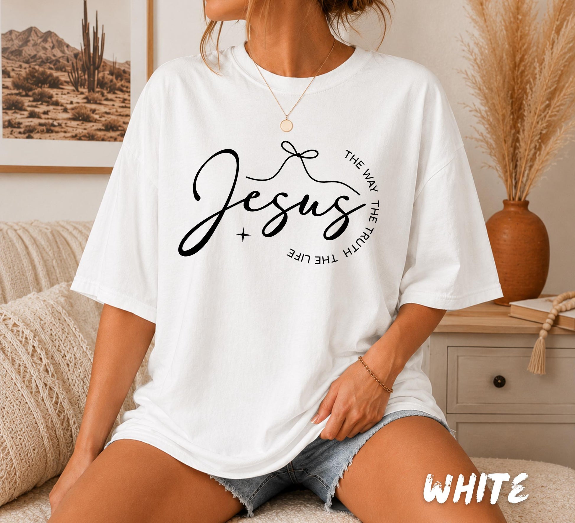 Woman wearing a white Comfort Colors Christian t-shirt featuring a minimalist "Jesus" script design with the words "The Way The Truth The Life" arranged in a circular layout.