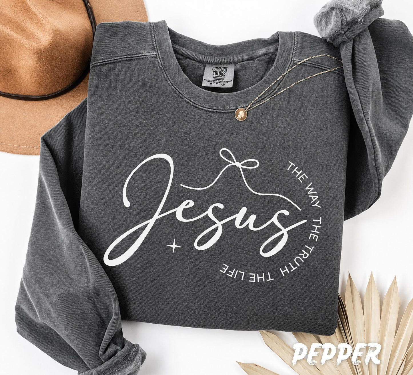 Folded Pepper Comfort Colors crewneck sweatshirt featuring a minimalist Christian "Jesus" typography design with "The Way The Truth The Life" in a modern circular composition.