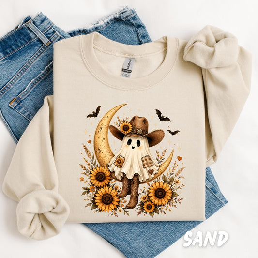 Sand Gildan sweatshirt featuring a cute cowgirl ghost wearing a western hat with sunflowers, cowboy boots, crescent moon, and bats, perfect for fall and Halloween.