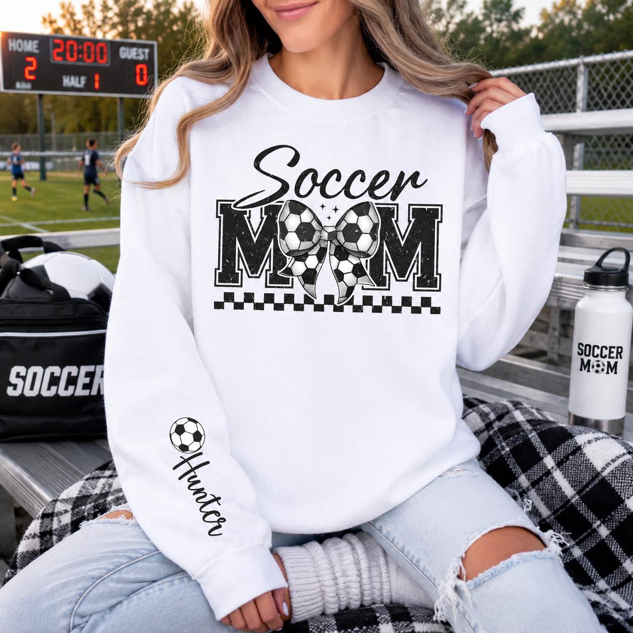 White Gildan crewneck sweatshirt featuring a personalized Soccer Mom design with customizable player name, perfect for game days and soccer season.