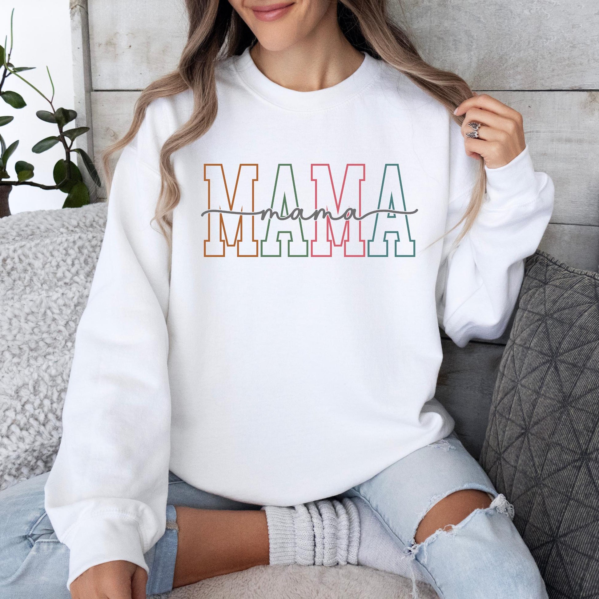 Woman wearing a white Gildan crewneck sweatshirt featuring a pastel varsity-style "Mama" graphic, perfect for Mother's Day, new moms, and everyday casual wear.