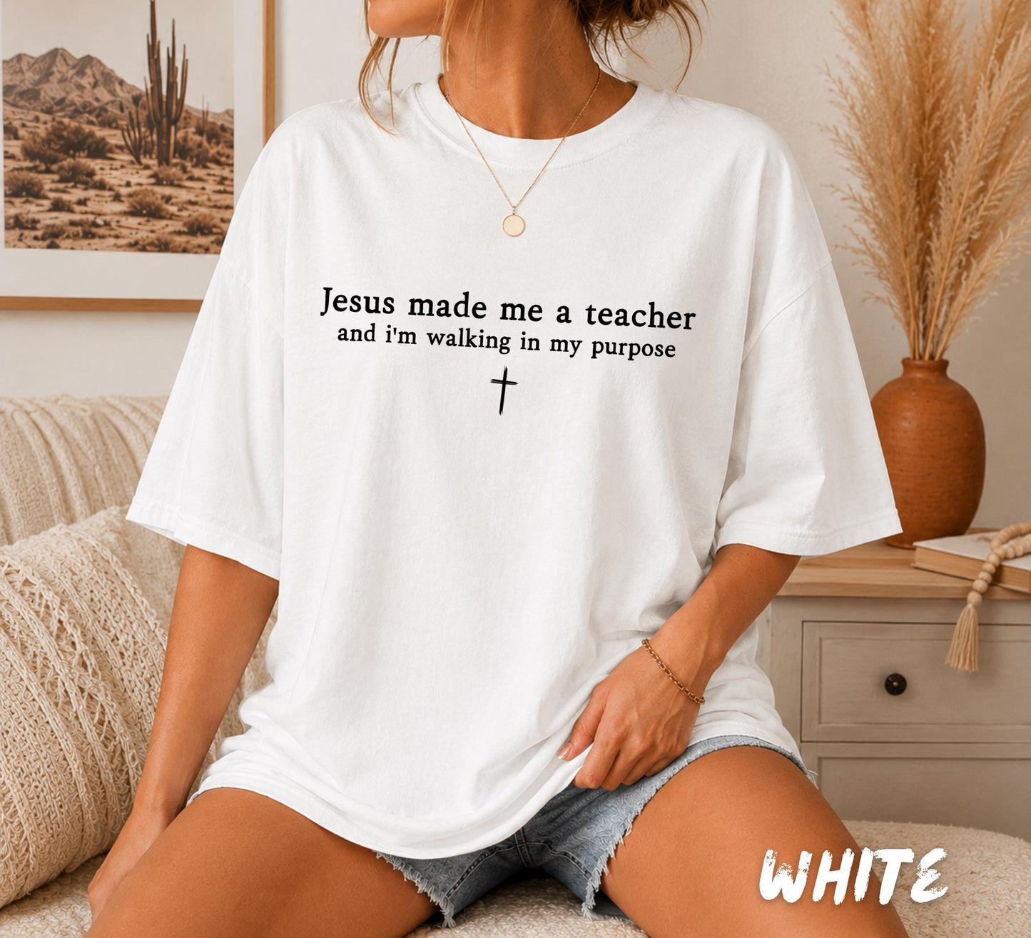 Woman wearing a white Comfort Colors Christian teacher t-shirt featuring the inspirational quote "Jesus Made Me A Teacher And I'm Walking In My Purpose" with a minimalist cross.