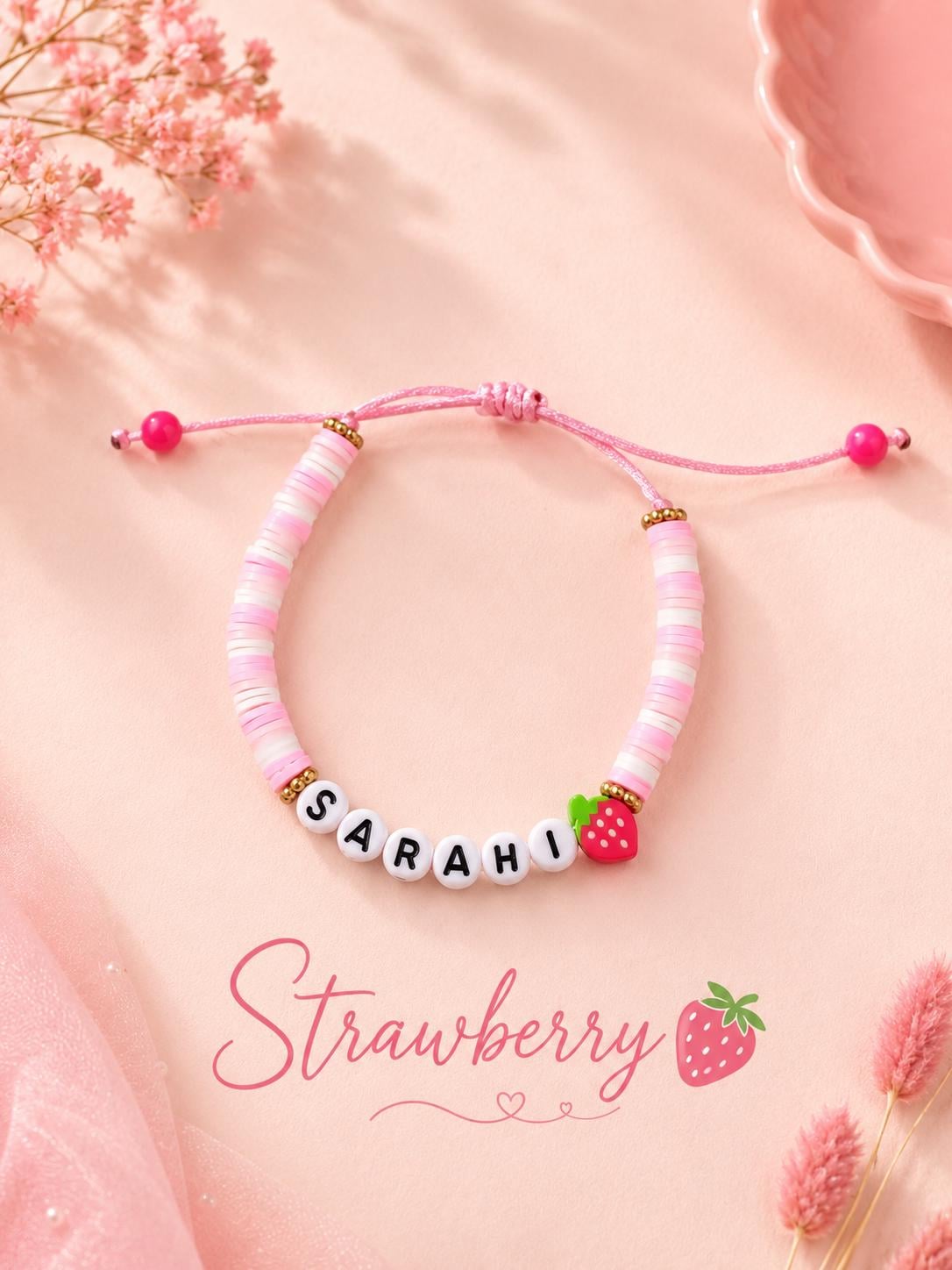 Close-up of adjustable sliding knot bracelet with custom name and strawberry charm.
