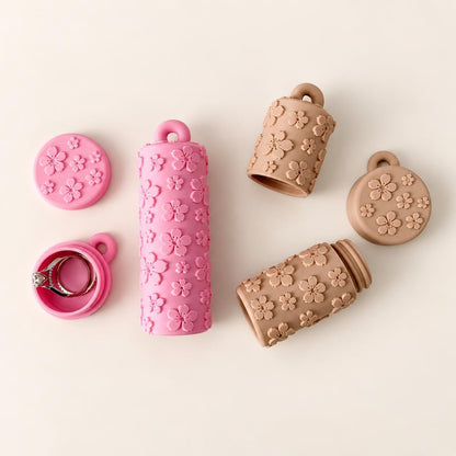 Matching pink and beige floral lip balm holders and round ring keeper keychains displayed on a warm ivory background.