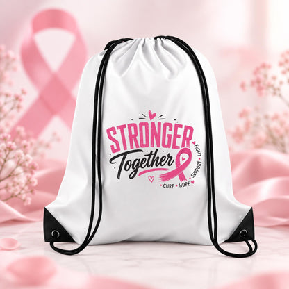 White drawstring backpack with pink and black Stronger Together breast cancer awareness design featuring a pink ribbon, displayed on a soft pink awareness background.