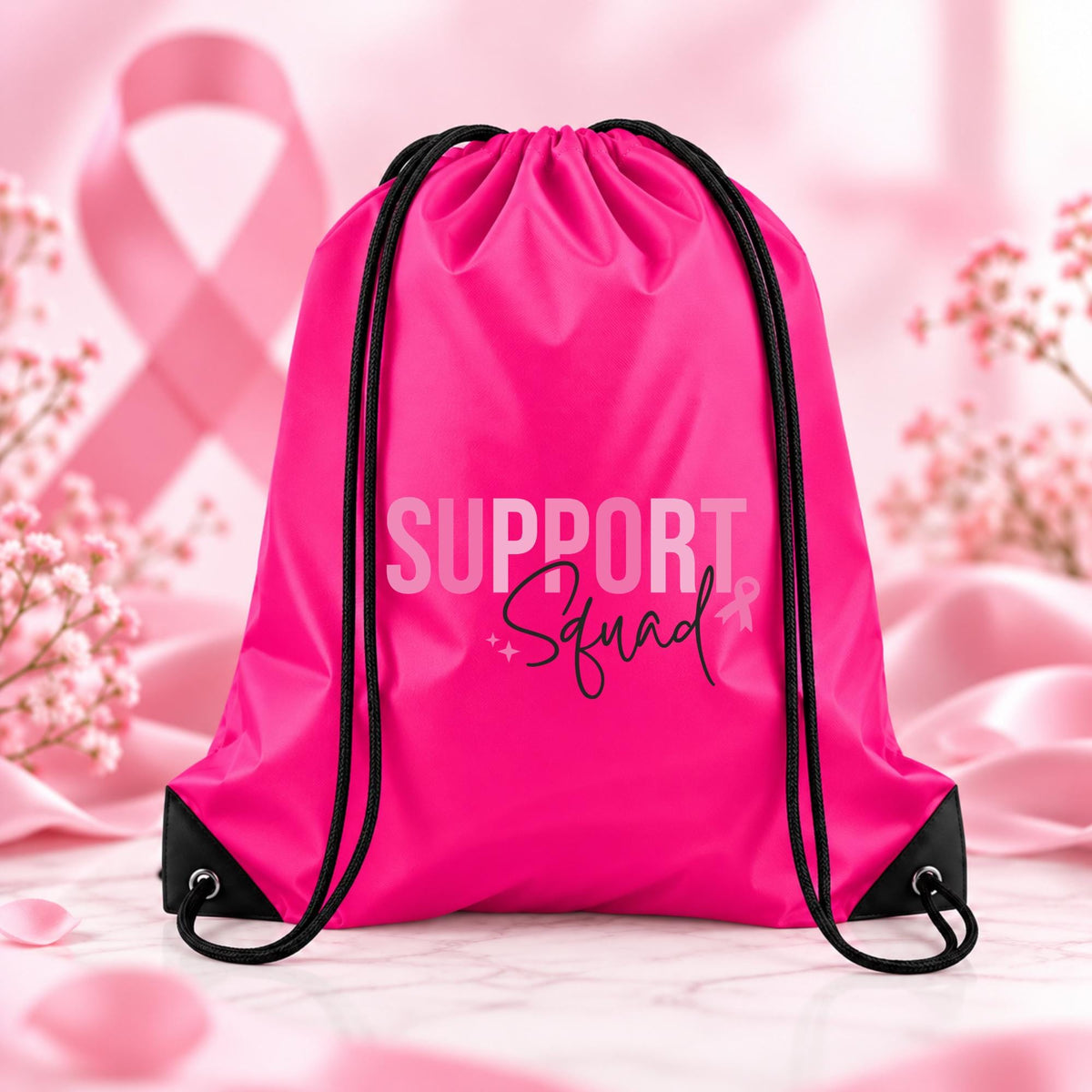 Bright fuchsia pink drawstring backpack featuring Support Squad breast cancer awareness typography with a small pink ribbon and black script lettering.